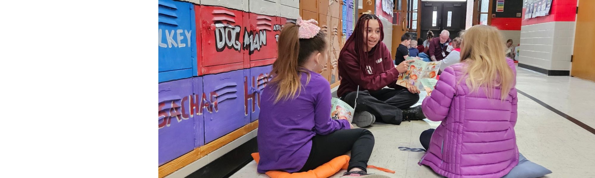 Student volunteer reads with elementary-age children during a school reading program, helping improve literacy and encourage a love of reading.