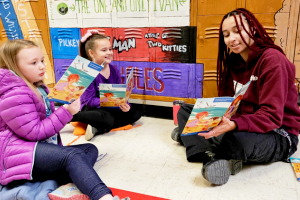 Volunteer reading with young students during a United Way Reading Adventure session in a classroom, engaging children in learning and literacy.
